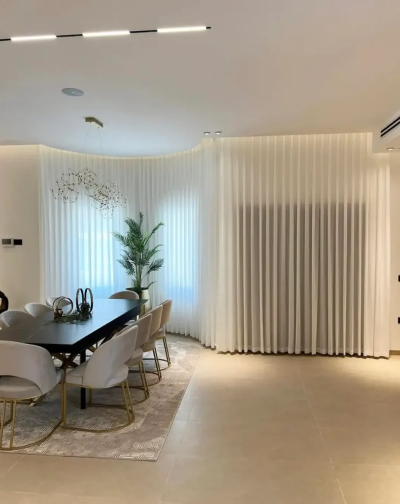 Modern dining room featuring a black table, white chairs, and sheer curtains by Window Treatments North Carolina.